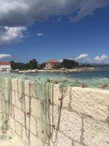a fence on a beach with the ocean and a house at Apartment Frano in Drače