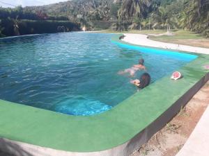 Ein Mann und eine Frau in einem Schwimmbecken in der Unterkunft Hotel Nautile in Sainte Marie