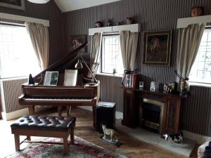 a living room with a piano and a fireplace at Thornley House in Hexham