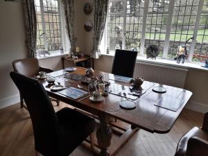 - une table en bois dans une chambre avec des chaises et des fenêtres dans l'établissement Thornley House, à Hexham