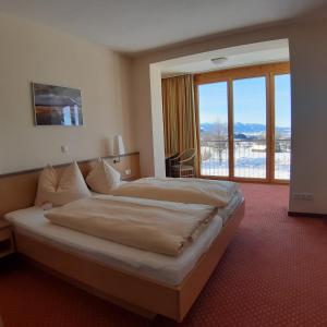 a bedroom with a large bed and a large window at AllgäuWeite in Sulzberg