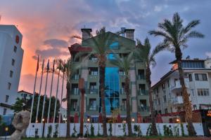 a building with palm trees in front of a sunset at Lara Park Hotel in Antalya
