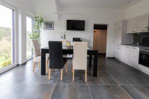 a kitchen and dining room with a black table and white chairs at FeWo Marita in Wimbach