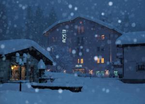 um edifício coberto de neve à noite em Hotel Post Sils Maria em Sils Maria