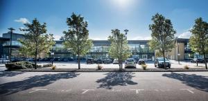 a parking lot with cars parked in front of a building at NIKSA Serviced Accommodation - Welwyn Garden City Business Park in Welwyn Garden City