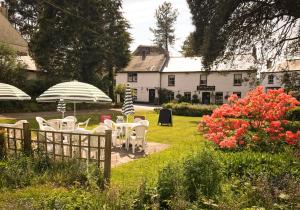 einen Garten mit Tischen und Sonnenschirmen vor einem Haus in der Unterkunft Elerkey Guest House in Veryan