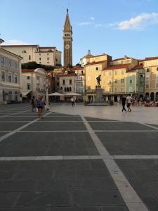 une place de la ville avec une tour d'horloge en arrière-plan dans l'établissement Tiny room, à Piran