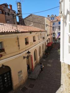 an alley in a city with buildings and a person standing in the street at Tiny room in Piran