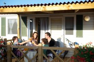 una famiglia seduta a un tavolo su un portico di Sirena Mobile Homes a Novigrad Istria