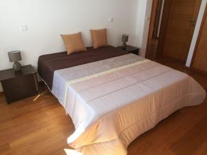 a large bed in a room with two night stands at Casa Carla in Guimarães