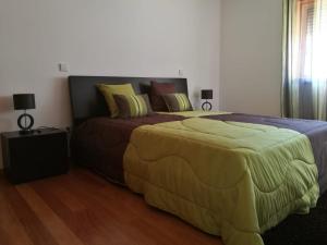 - une chambre avec un grand lit et une couverture jaune dans l'établissement Casa Carla, à Guimarães