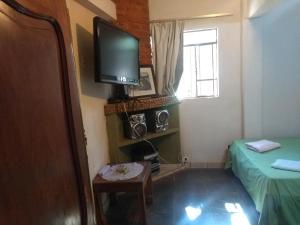 a room with a tv and a bed and a window at Casas do Adriano in Conceição da Ibitipoca