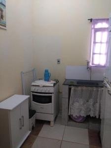 a kitchen with a stove and a sink and a window at Casas do Adriano in Conceição da Ibitipoca