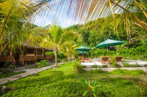 un complexe avec une cour dotée de chaises et de parasols dans l'établissement Ruji Ananta Cottage, à Nusa Penida