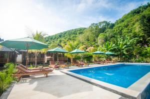 - une piscine avec chaises longues et parasols dans l'établissement Ruji Ananta Cottage, à Nusa Penida