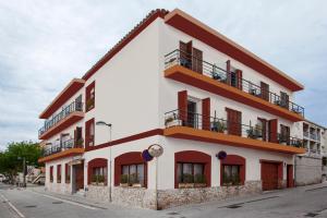 un edificio blanco con ventanas rojas y balcones. en Hostal Residencia Catalina en Palamós