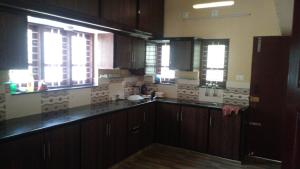 a kitchen with wooden cabinets and two windows at Sowparnika N.V Nagar Peroorkada in Trivandrum