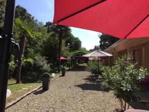 un patio con una sombrilla roja y algunas plantas en Résidence EMILIA en Santa-Maria-Poggio