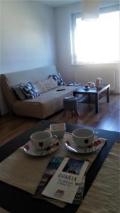 a living room with two cups and a table at Sympatyczny Apartament in Gdańsk