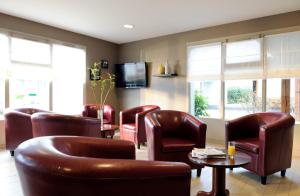 a waiting room with leather chairs and a tv at Campanile Château-Thierry in Château-Thierry