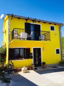a yellow house with a balcony on top of it at Apartment Josipa in Premantura