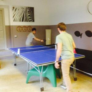 Due uomini che giocano a tennis su un tavolo da ping pong di Panda Hostel a Milano