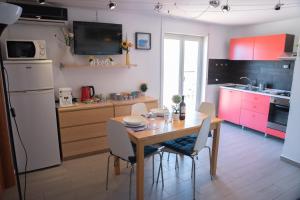 una cucina con tavolo in legno e una cucina con armadietti rosa di Attico Panoramico Agrigento a Agrigento