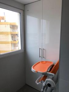 einen orangenen Stuhl in einem Zimmer mit Fenster in der Unterkunft Apartamento Cancun 7 Playa de Gandía in Playa de Gandia