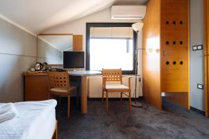 a bedroom with a desk with two chairs and a bed at Hotel GH Kolinska in Bled