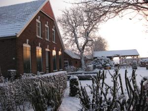 una casa con nieve en el suelo delante de ella en 't Lankhof, en Aalten