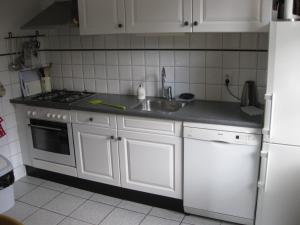 uma cozinha com armários brancos, um lavatório e um frigorífico em 't Lankhof em Aalten