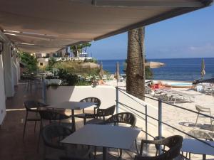 un patio con tavoli, sedie e spiaggia di Hotel Gran Paradiso a Ischia