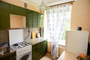a kitchen with green cabinets and a stove and a window at KvartiraSvobodna - Apartment at Bolshoy Kondratyevskiy in Moscow