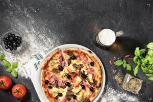 a pizza on a plate on a table with a glass of milk at Alloggi The Towers in Montebello Vicentino