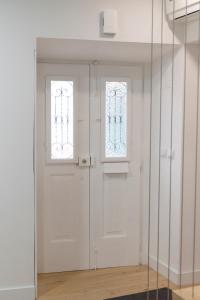 a white door in a room with two windows at Évora Art&Accommodation in Évora