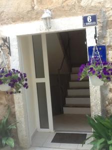 una entrada a un edificio con escaleras y flores púrpuras en Apartments Senko, en Trpanj