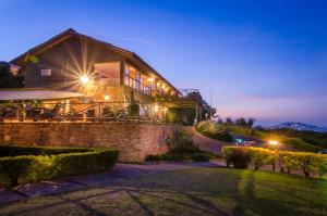 une maison avec des lumières sur son côté la nuit dans l'établissement Cassia Lodge, à Munyonyo