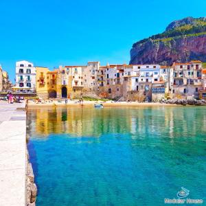 a group of buildings on a beach next to the water at Modular House in Cefalù