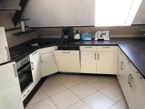 a kitchen with white cabinets and black counter tops at Ferienwohnung am Rande der Dübener Heide in Laußig