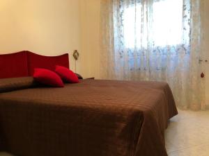 Schlafzimmer mit einem Bett mit roten Kissen und einem Fenster in der Unterkunft Dimora del '500 -City Apartment San Vito in San Vito dei Normanni