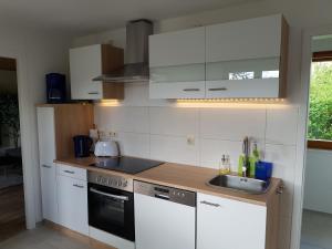a kitchen with white cabinets and a sink at Feriendomizil am Zeulenrodaer Meer in Zadelsdorf