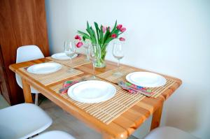 a table with plates and wine glasses and a vase of flowers at Apartament IKAR blisko morza in Pobierowo