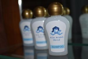 a group of white shampoo bottles on a glass shelf at Vila Arsovi in Ohrid +32 photos