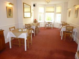 a dining room with tables and chairs and windows at Southernhay Guest House in Bournemouth