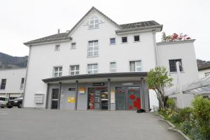 a white building with a parking lot in front of it at Business Apartments Reichenburg in Reichenburg