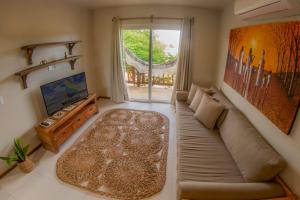 a living room with a couch and a tv at Villa das Palmeiras Jeri in Jericoacoara