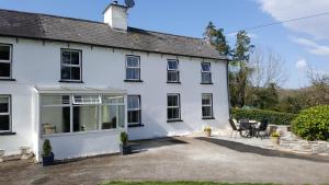 a white house with a patio in front of it at Gortamullen House, Kenmare in Kenmare