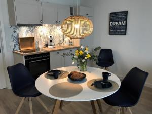 a kitchen with a white table with chairs and a vase of flowers at SEASIDE APARTMENTS - BEACHHOUSE BLUE in Eckernförde +8 photos