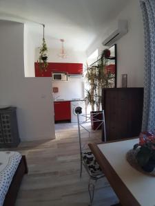 - une cuisine et un salon avec des armoires rouges et une table dans l'établissement Studio Lou Nidou, Nice Centre, à Nice
