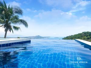 a swimming pool with a palm tree and the ocean at Villa Ocean Heaven in Chaweng Noi Beach